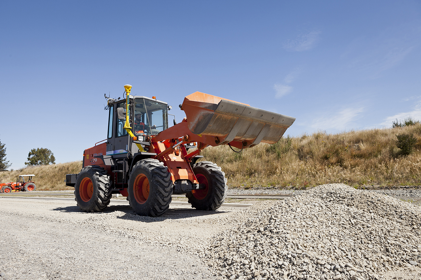 Pá de Rodas equipada com o sistema 3D Trimble Earthworks a trabalhar num terreno de construção. A máquina está a mover cascalho e a demonstrar a sua capacidade de nivelamento preciso do solo