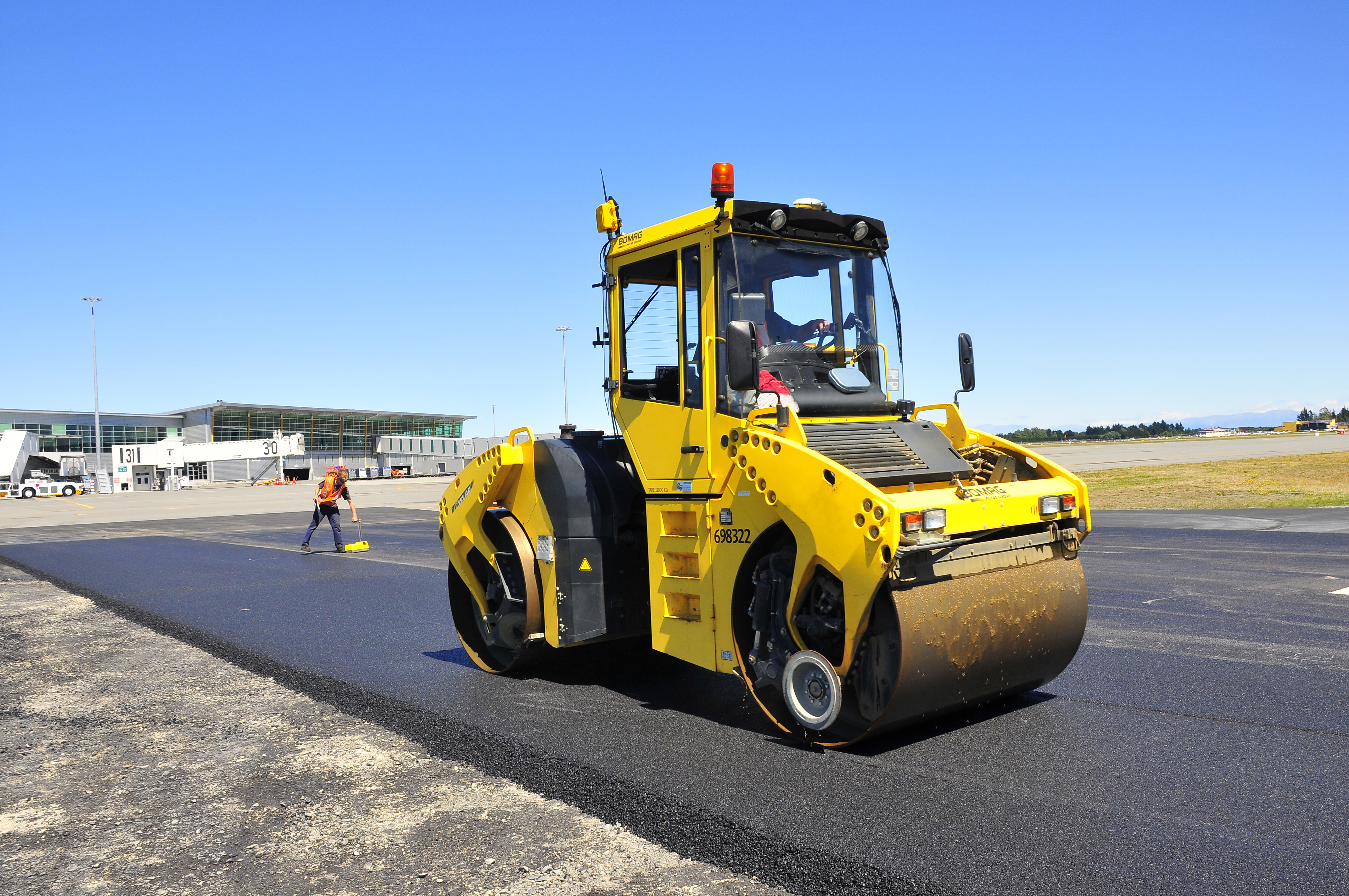 Compactador amarillo bomag en acción sobre asfalto, con tecnología de sistema 3D para una compactación precisa y eficiente