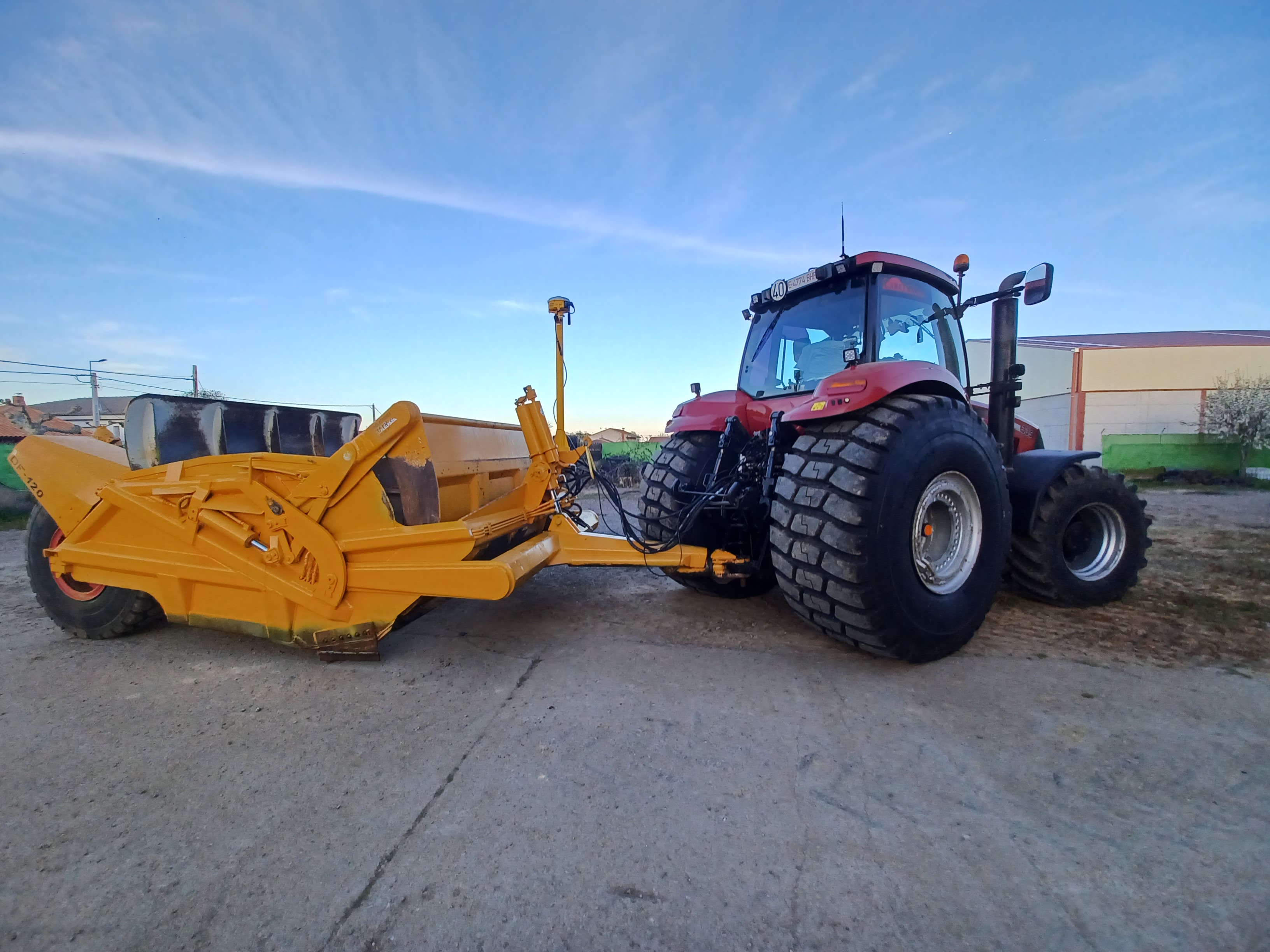 Tractor conectado a un implemento de control de nivelación 3D en color amarillo, demostrando la integración de la tecnología de Trimble en maquinaria agrícola para mejorar la eficiencia y productividad en las operaciones de nivelación