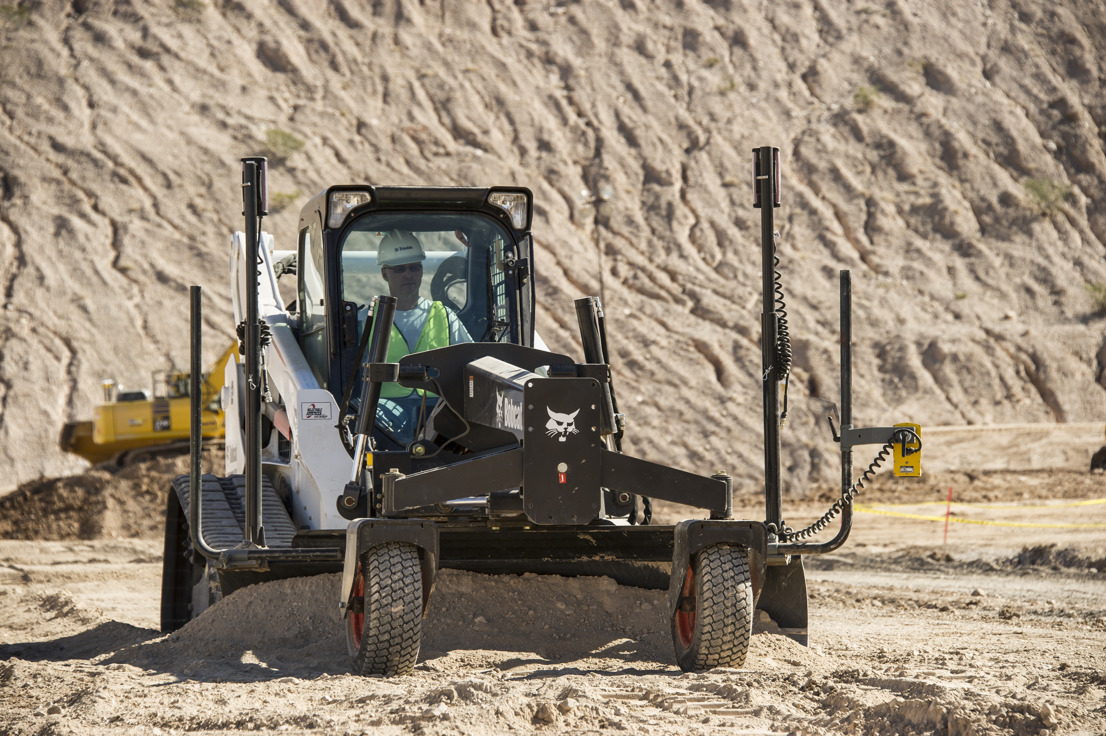 Mini carregadora em funcionamento num estaleiro de construção e equipada com sensores e controlos do Trimble Earthworks 2D System