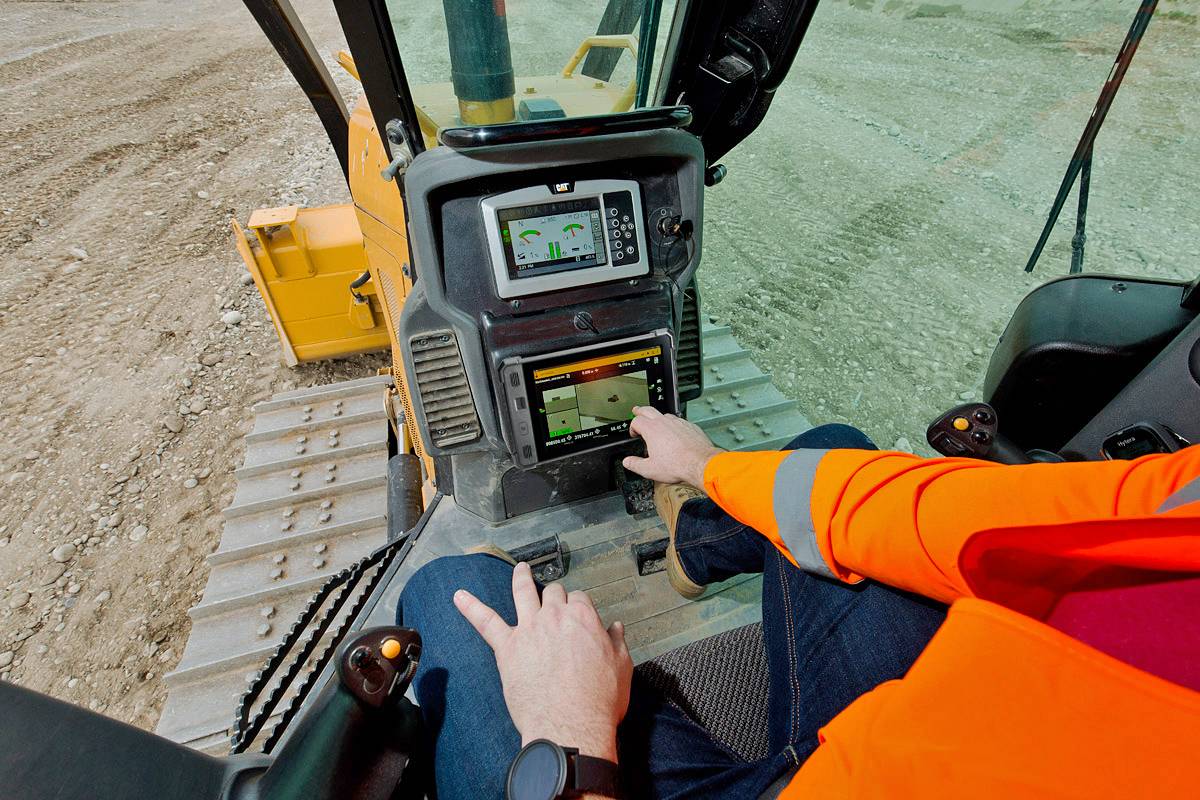 Operador a interagir com o sistema Trimble Earthworks 3D através de um ecrã tátil dentro da cabina de um Bulldozer