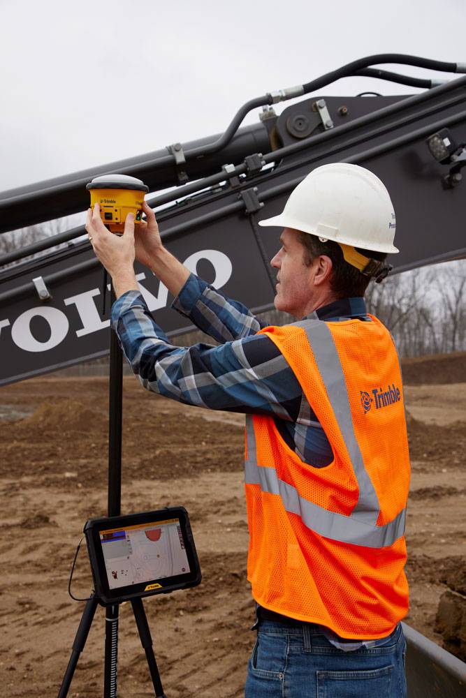 Operador a colocar o Trimble Siteworks Machine Guidance Module numa antena recetora