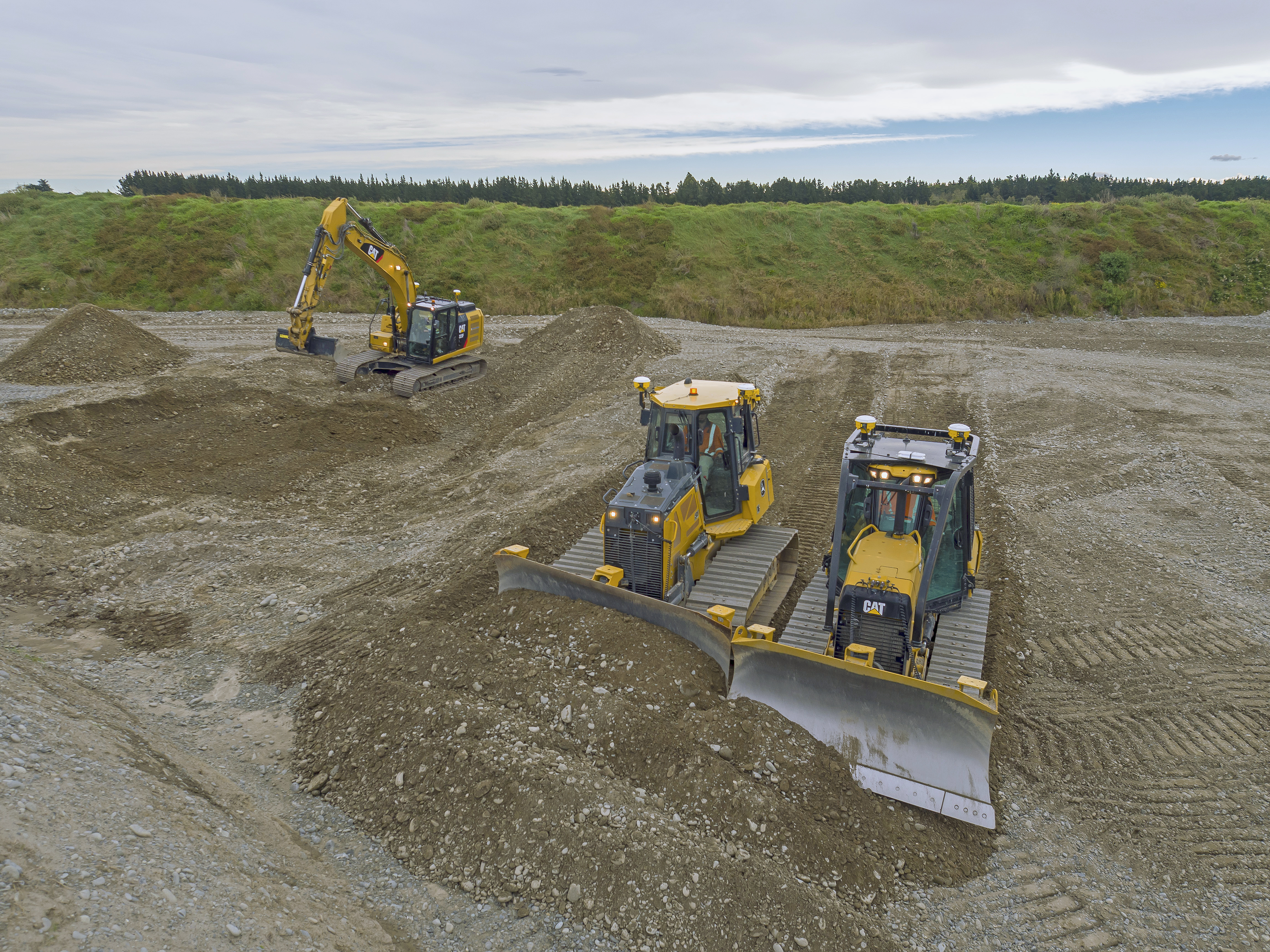 Maquinaria pesada de SITECH realizando movimiento de tierras en un amplio terreno. Excavadora y bulldozers Caterpillar trabajando eficientemente en proyectos de construcción y desarrollo